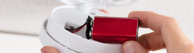 | AmeriSpec Home Inspection Service Smoke detector with red battery being replaced